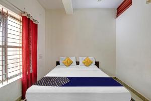 a bedroom with a bed with a red curtain at Hotel O Vishu Moni Residency in Mysore