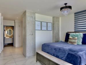 Un dormitorio con una cama azul y una lámpara de araña. en Luxury Beachfront Condo 3BR 3BA with stunning views, en Tijuana