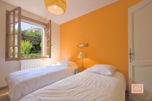 two beds in a room with an orange wall at Maison de la Rade, sea view and air conditioning in Saint-Mandrier-sur-Mer