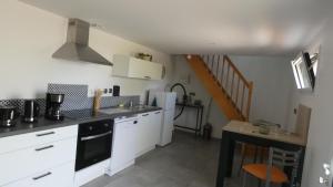 une cuisine avec des placards blancs, une table et un escalier dans l'établissement Au long du cher, à Véretz