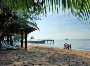 a group of people standing on a beach with a pier at PD DWharf Hotel Suite & Serviced Residence in Port Dickson