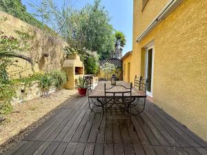una terrazza in legno con tavolo e sedie. di Maison Occitane avec Piscine a Béziers