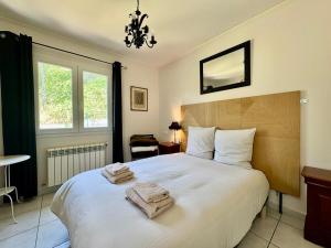 una camera da letto con un grande letto bianco con asciugamani sopra di Maison Occitane avec Piscine a Béziers Altre 41 foto