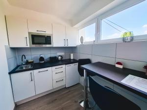 a kitchen with white cabinets and a table and a microwave at PartON Keszthely in Keszthely +11 photos