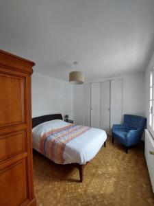 ein Schlafzimmer mit einem Bett und einem blauen Stuhl in der Unterkunft Maison de pêcheur - Quartier Croix de Vie in Saint-Gilles-Croix-de-Vie