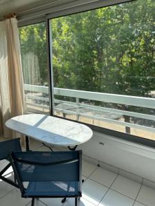 a table and a chair in front of a window at Clube 6 T1 piscine parking in La Grande-Motte