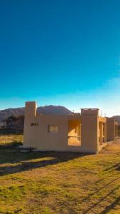 una piccola casa bianca con montagne sullo sfondo di Cabañas Valle del Búho a Potrero de los Funes