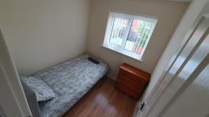 a small bedroom with a bed and a window at Beautiful 3 bedroom House Manchester in Little Hulton