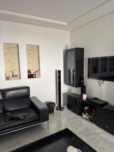 a living room with a black leather couch and a flat screen tv at Paradise in Bin Rhilouf