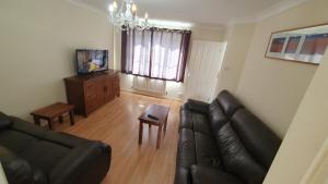 a living room with a black leather couch and a table at Beautiful 3 bedroom House Manchester in Little Hulton