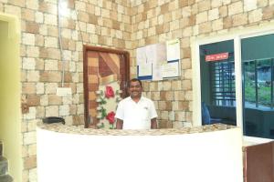 a man standing in front of a brick building at Sky Touch Inn in Yercaud