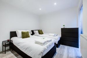 zwei Betten in einem Schlafzimmer mit weißen Laken und grünen Kissen in der Unterkunft Sleek 3 Bedroom 6 Beds 2 Bath Home in Colchester