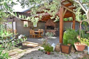 a patio with a wooden pergola with a table and a fireplace at Apartments Vretenar in Novigrad Istria