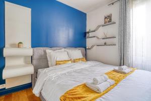 1 dormitorio con paredes azules y 1 cama con toallas. en Reflet Royal - 10 min de Paris - Netflix, en Alfortville