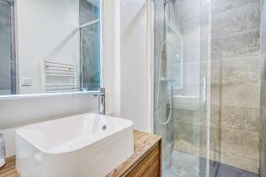 Un baño blanco con ducha y lavabo. en Reflet Royal - 10 min de Paris - Netflix, en Alfortville