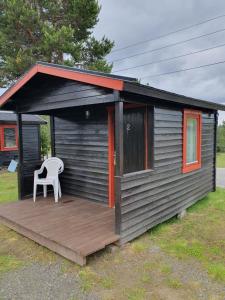 a small cabin with a chair on a wooden deck at Bjørgebu Camping AS in Mysusæter +11 photos