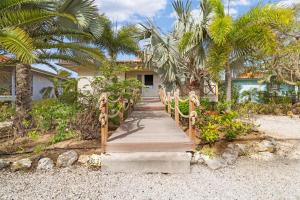 a wooden walkway leading to a house with palm trees at Villa Happy Turtle with a spectacular ocean view in Kralendijk
