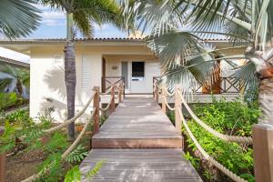 a wooden walkway leading to a house with palm trees at Villa Happy Turtle with a spectacular ocean view in Kralendijk
