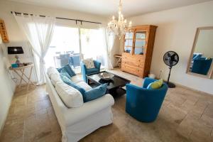 a living room with a white couch and blue chairs at El Trupial in Kralendijk