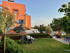 a yard with chairs and an umbrella and a building at La Perle De Briech in Asilah