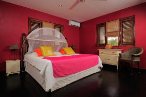 Un dormitorio rojo con una cama blanca con almohadas amarillas. en Casa El Tropico, en Kralendijk 17 fotos más