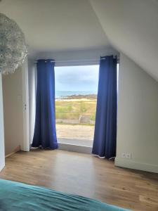 a bedroom with blue curtains and a large window at Ti Poulfoen in Plouescat