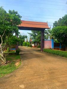 a building with a red roof next to a road at Rawinnipha's Resort & Garden Khonkaen in Khon Kaen