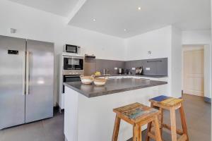 a kitchen with a refrigerator and a counter with two stools at Casa Pimienta in Water Villas in Kralendijk