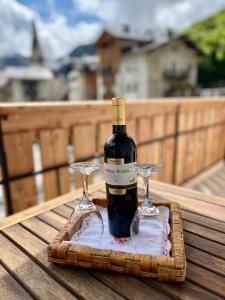 a bottle of wine and two wine glasses on a table at My Dolomites Home in Livinallongo del Col di Lana