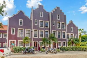 ein lilafarbenes Gebäude mit davor geparkt in der Unterkunft Caribbean Court Apartment Djòdjò in Kralendijk