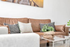 ein Wohnzimmer mit einem braunen Sofa und einem Tisch in der Unterkunft Caribbean Court Apartment Djòdjò in Kralendijk