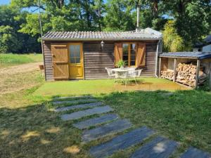 a small wooden cabin with a table and a patio at La maison verger in La Rochefoulques