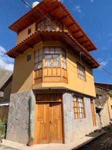 ein großes Haus mit Holztüren und Fenstern in der Unterkunft Juliet's House in Ollantaytambo