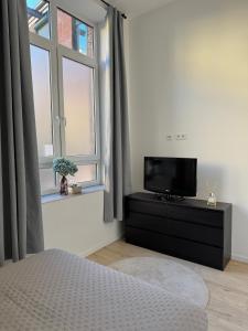 a bedroom with a tv on a dresser next to a window at Heaven Homes - Privatzimmer mit Bad in der Nähe von Hbf in Düsseldorf
