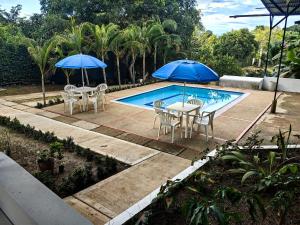 two tables and chairs with umbrellas next to a pool at Villa Stefy in San Antonio