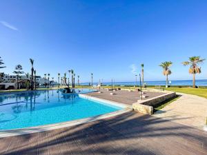 a swimming pool next to the beach with palm trees at Marina beach pied dans l eau in Marina Smir