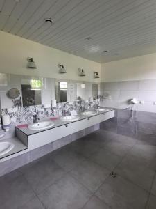 a bathroom with four sinks and a row of mirrors at Przyczepa campingowa in Grzybowo
