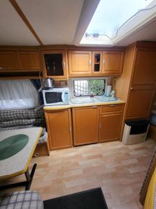 an rv kitchen with wooden cabinets and a sink at Przyczepa campingowa in Grzybowo +12 photos
