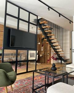 een woonkamer met een trap en een glazen tafel bij Engadin's Family Apartment in Jahorina