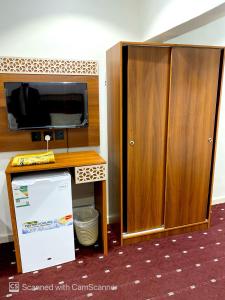 a room with a tv and a wooden cabinet at فندق مواسم الخير الدولية in Az Zahrāʼ
