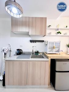a kitchen with wooden cabinets and a sink at Modern Studio Comfort at Bernwood Tower in Iloilo City