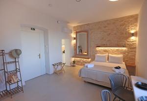 a bedroom with a bed and a stone wall at Hermosa Seaside Living in Ermoupoli