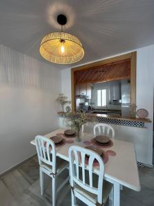 a dining room table with white chairs and a light fixture at APARTAMENTO LUXURY Golf Center in Roquetas de Mar