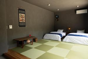 a bedroom with two beds and a table in it at 陽月-Hizuki- in Nakijin