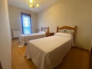 a room with two beds with white sheets and a window at Casa Rural Las Eras I 