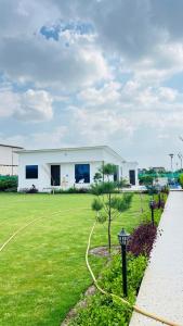 a white house with a hose in a yard at The Dhaulidhar Farm in Greater Noida