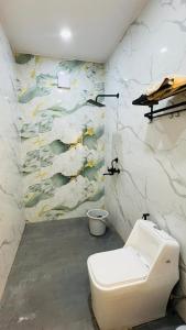 a bathroom with a white toilet and a mural at The Dhaulidhar Farm in Greater Noida