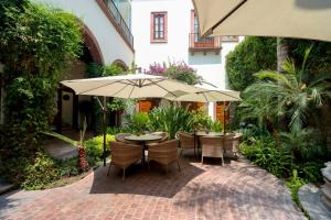 an outdoor patio with tables and chairs and an umbrella at Hotel Casa Blanca 7 in San Miguel de Allende