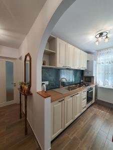 an arched kitchen with white cabinets and a sink at BicazApart in Bicaz