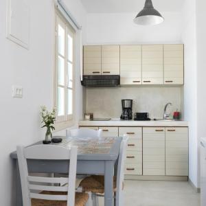a kitchen with white cabinets and a table and chairs at Fyroi Studio in Loutra +13 photos